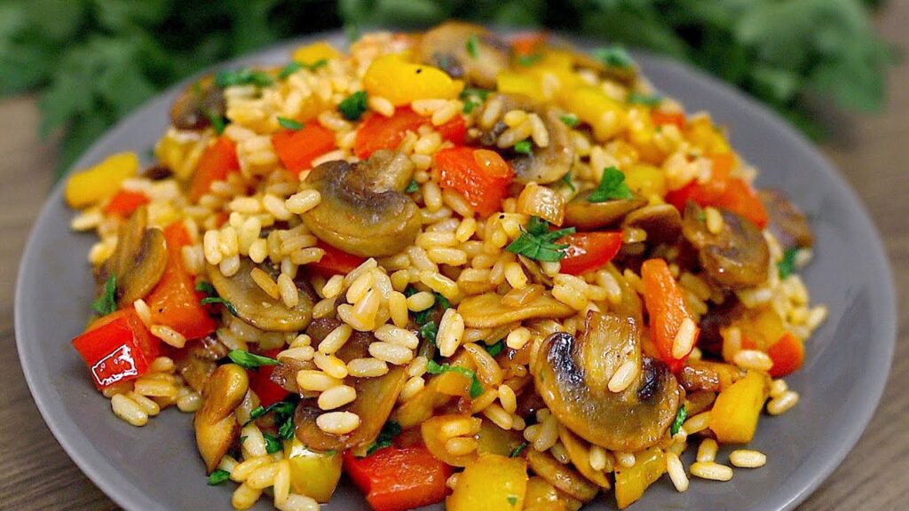 Eine schnelle und leckere beilage! reis mit pilzen und gemüse in einer pfanne!